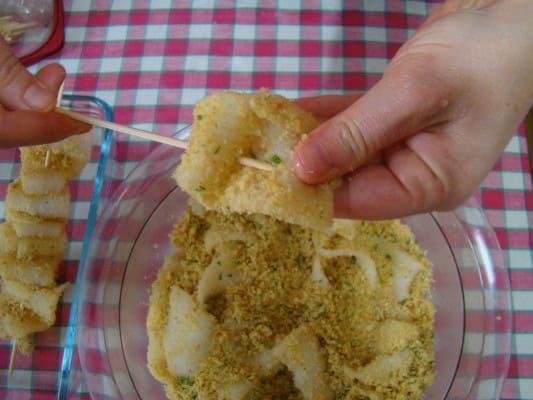 Preparazione degli spiedini di calamari alla romagnola con sfondo tovaglia casalinga