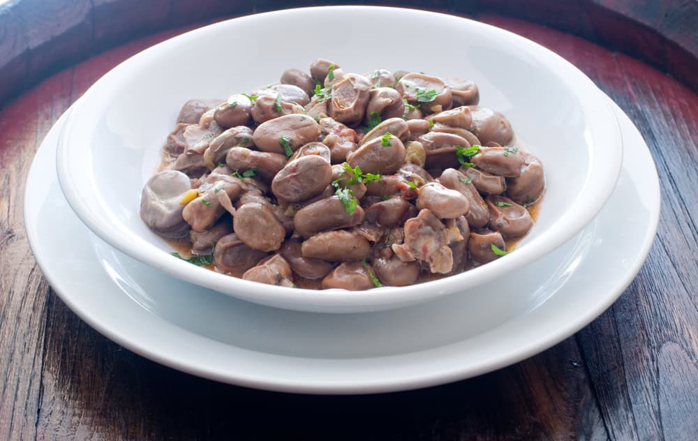 Fava ngreccia marchigiana, insalata di fave lessate e condite con salsa cruda di aglio, acciughe, capperi, prezzemolo e aceto, servita in piatto fondo bianco