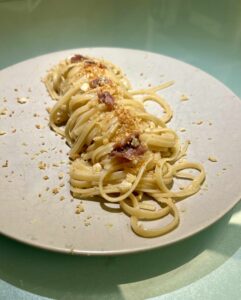Linguine burro acciughe e limone con mollica croccante, impiattate in stile gourmet a nido steso per lungo.