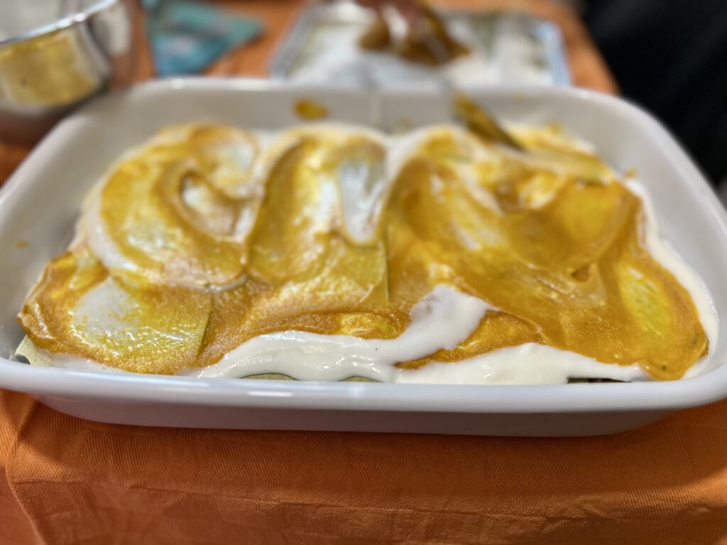 Lasagne in teglia con besciamella e crema di zucca nello strato iniziale.