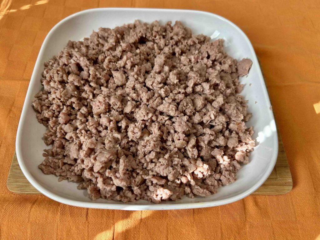 Salsiccia sbriciolata cotta e dorata su un piatto.