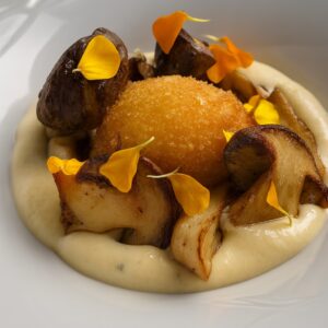 Tuorlo croccante dorato servito su fonduta di Parmigiano con porcini scottati e fiori eduli