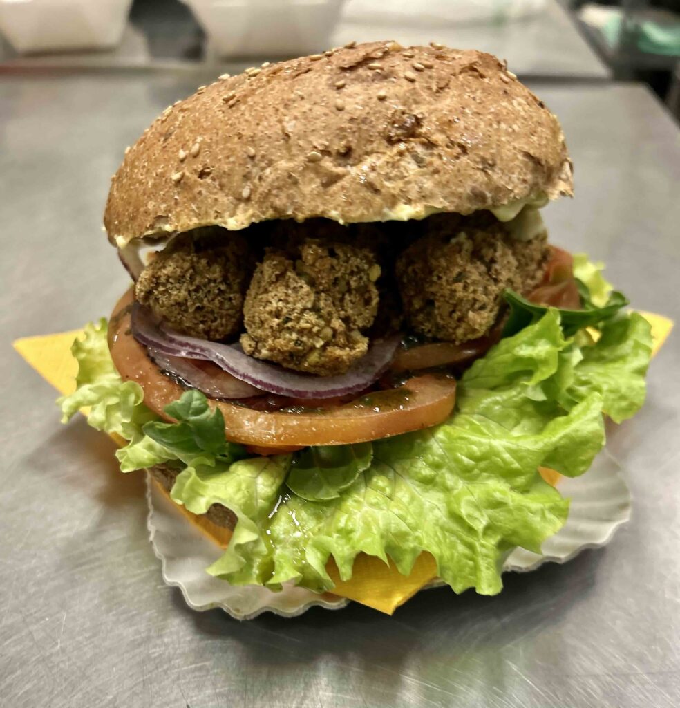 Hamburger gourmet vegano con falafel di ceci, pomodori grigliati, spinacini freschi e maionese vegana al curry
