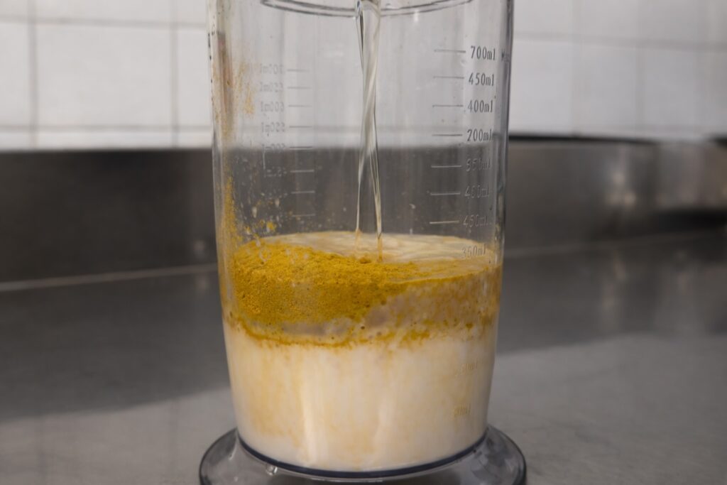 Ingredienti per la maionese vegana al curry nel bicchiere del minipimer