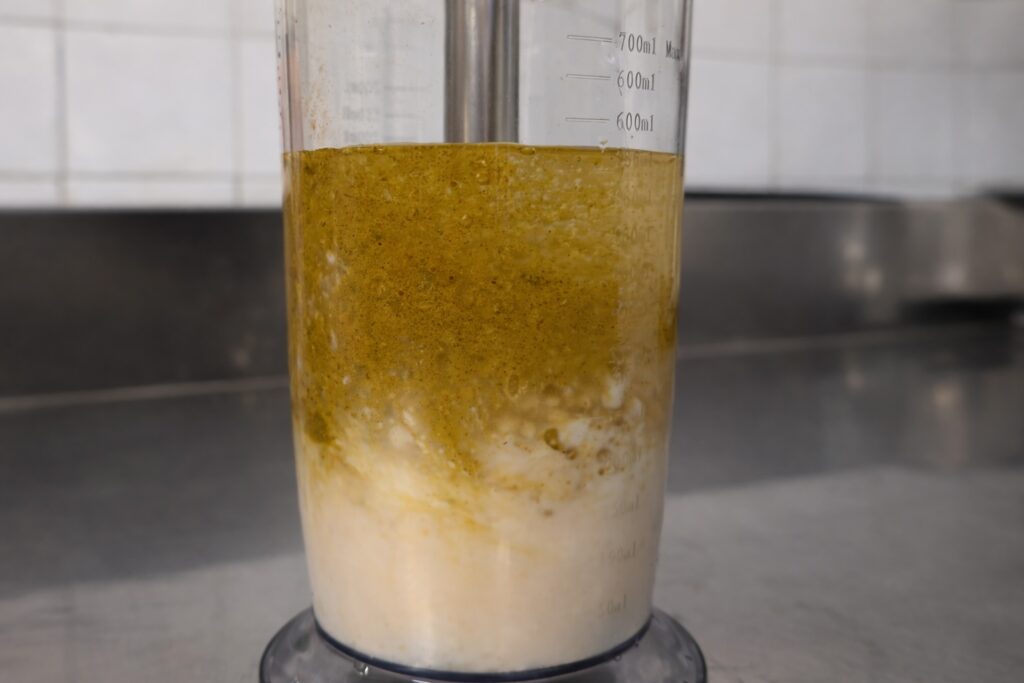 Inizio emulsione della maionese vegana al curry con minipimer sul fondo